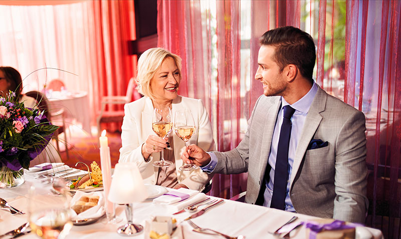 Mutter und Sohn stoßen im Restaurant mit Weinglas an