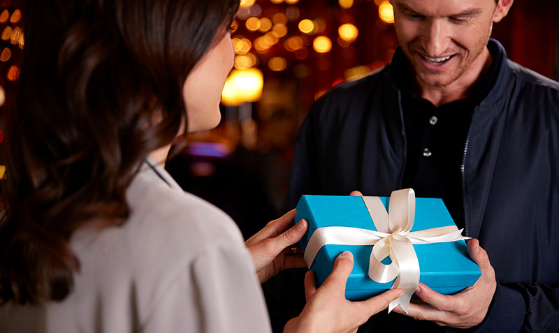 Tochter übergibt blaue Geschenkbox an Vater